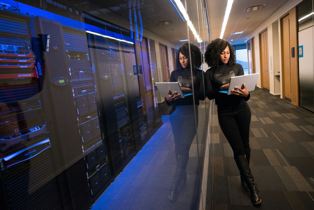 Two colleagues reviewing systems on laptops in a server corridor